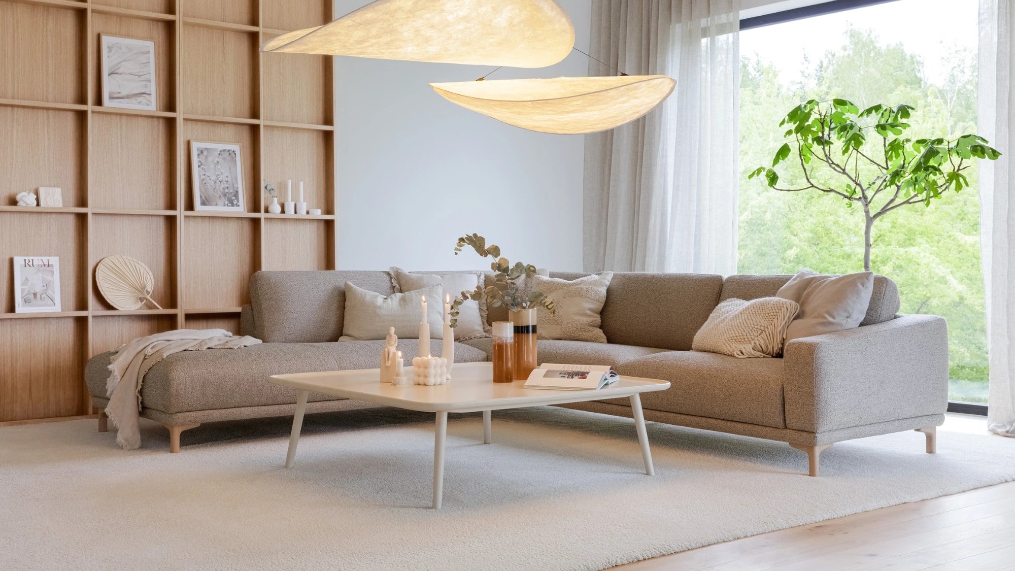 Modern living room with a beige sectional sofa, coffee table, and decorative elements.