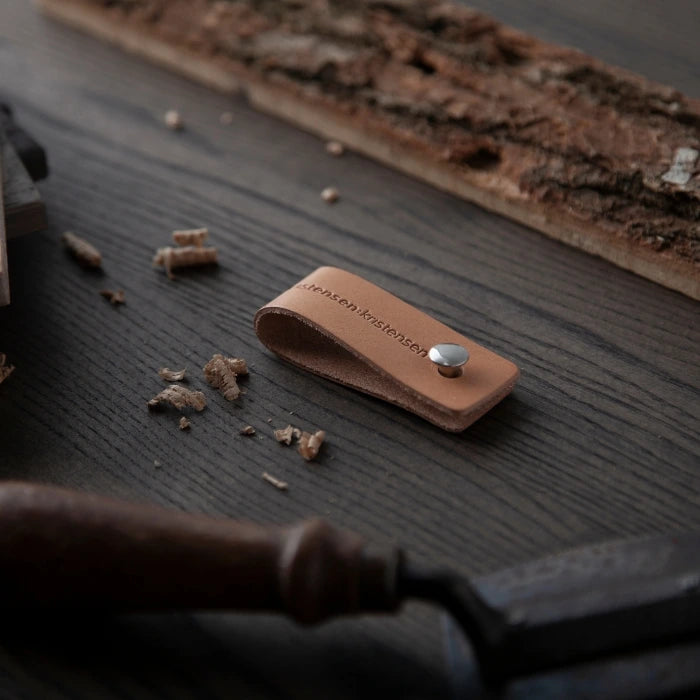 Brown leather case with a metal button on a wooden surface