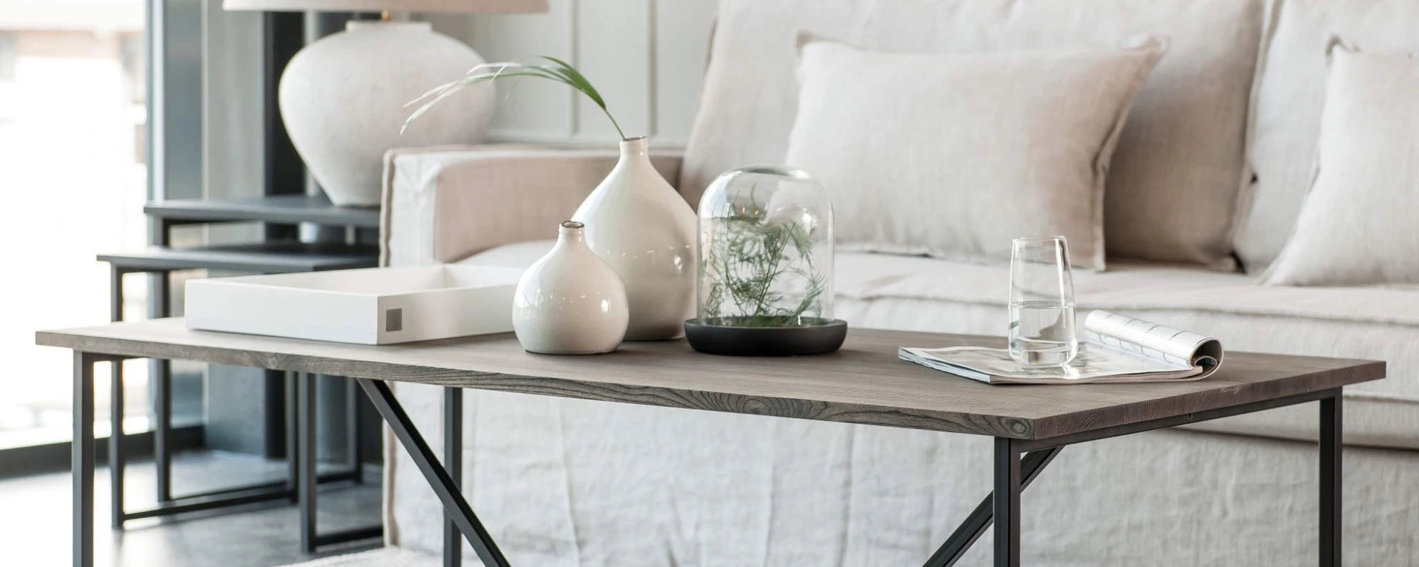 Modern living room with a coffee table, decorative vases, and a sofa.