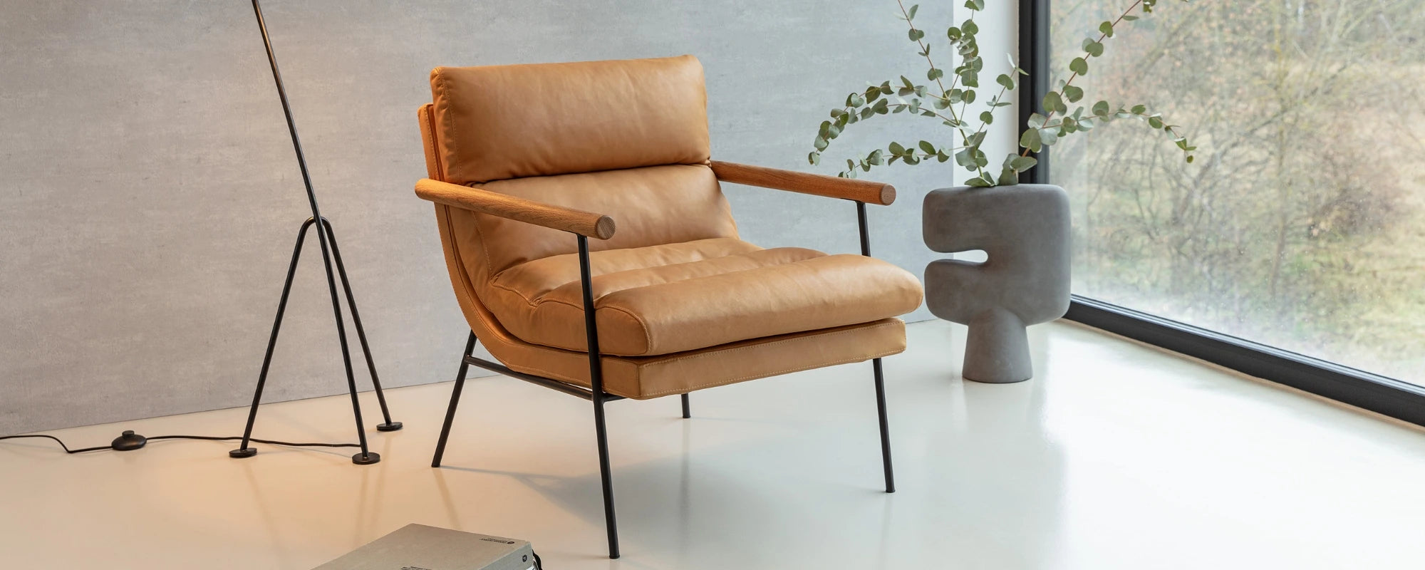 Brown leather armchair in a modern room with a large window