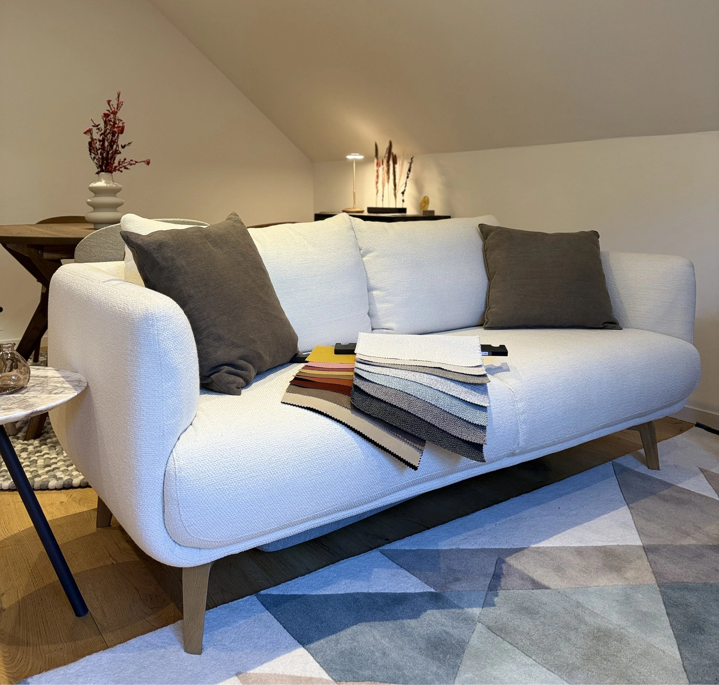 Modern living room with a white sofa, gray cushions, and a geometric rug.