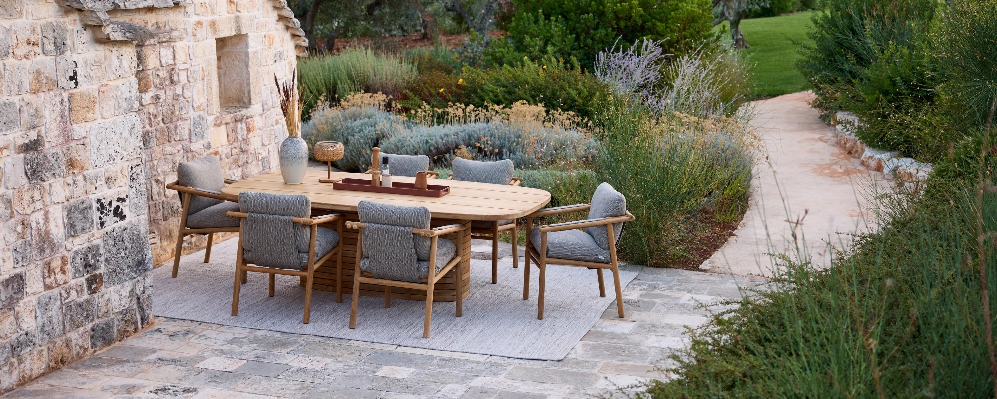 Outdoor dining area with wooden table and chairs near a stone building.