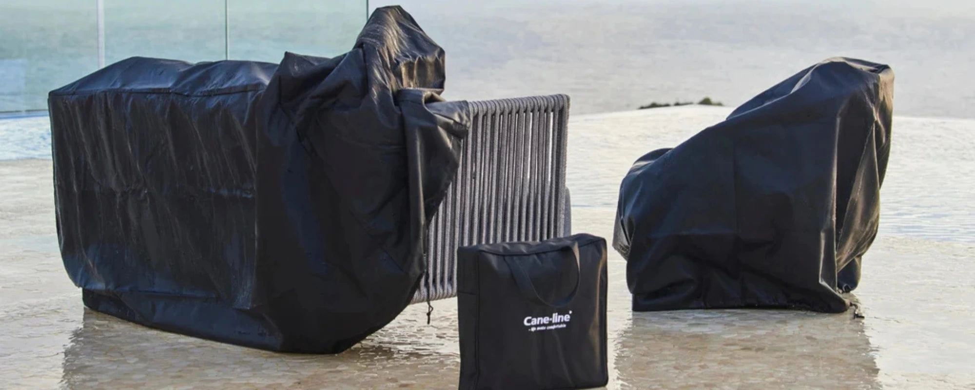 Black outdoor furniture covers on a patio with a clear sky background